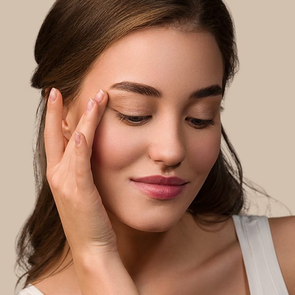 beauty-model-woman-with-healthy-natural-make-up-clean-skin-touching-her-face-color-background-brown